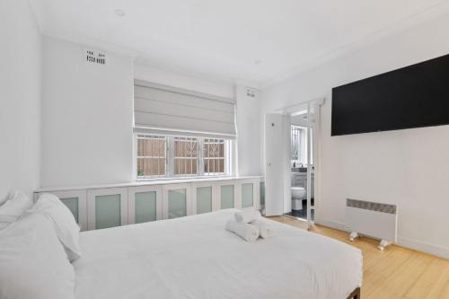 a white bedroom with a large bed and a flat screen tv at Pet-Friendly Home Just Minutes from Bondi Beach in Sydney