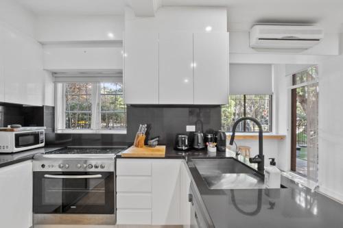 a white kitchen with a stove and a sink at Pet-Friendly Home Just Minutes from Bondi Beach in Sydney
