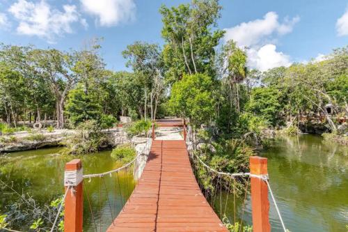 a wooden bridge over a river with trees at Departamento 2, Tulum Country Home, con Muelle de Pesca, Club de Playa, Alberca, Cenote y Campo de Golf, Contrata Day Pass Bahia Principe in Tulum