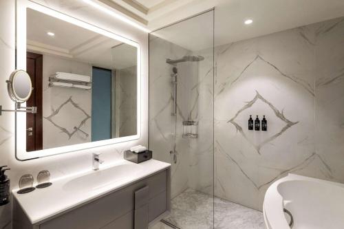 a bathroom with a sink and a glass shower at Wyndham Grand Doha West Bay Beach in Doha