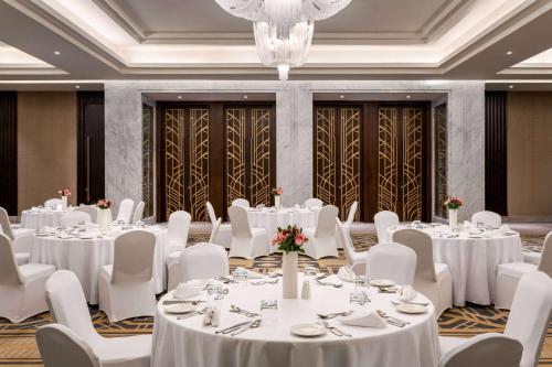 a banquet hall with white tables and chairs and a chandelier at Wyndham Grand Doha West Bay Beach in Doha