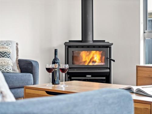 a living room with a fireplace and two glasses of wine at Reubs - Margaret River in Margaret River Town