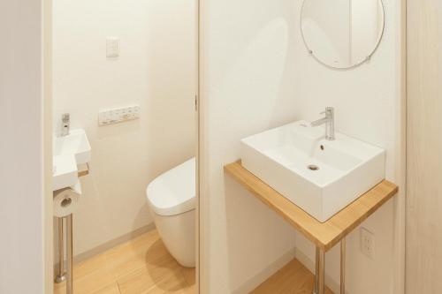 a white bathroom with a sink and a toilet at しお活Harbor in Kumage