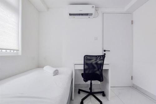 a bedroom with a desk and a chair next to a bed at Spacious and Elegant 3BR Loft at Kingland Avenue Apartment By Travelio in Tangerang