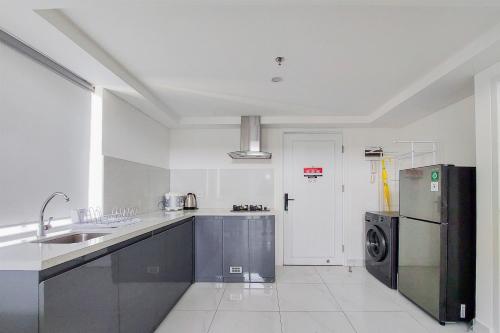 a kitchen with a sink and a refrigerator at Spacious and Elegant 3BR Loft at Kingland Avenue Apartment By Travelio in Tangerang