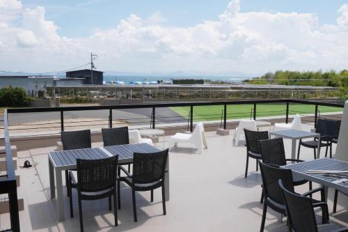 a patio with tables and chairs on a balcony at J-Hoppers Lake Biwa Guesthouse in Otsu