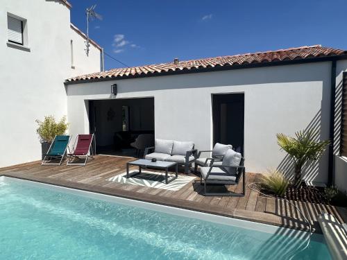 une terrasse avec des chaises et une piscine à côté d'une maison dans l'établissement L'Ayucca, à Saint-Jean-de-Monts