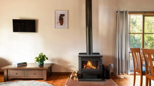 a living room with a stove and a table at Elsie Cottage in Drummond