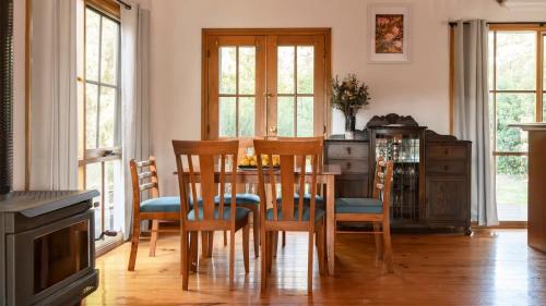 a dining room with a table and chairs and windows at Elsie Cottage in Drummond