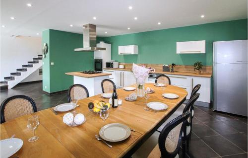 a wooden table with chairs and a kitchen with green walls at Nice Home In Suze-La-Rousse With Wifi in Suze-la-Rousse