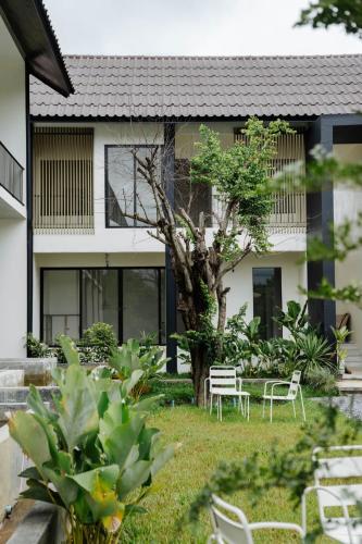 a garden with chairs and a tree in front of a building at Shanti-Retreat Hotel in Pua