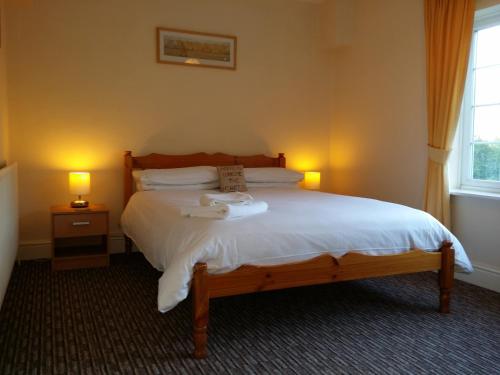 a bedroom with a large bed with two lamps at Guesthouse At Rempstone in Loughborough
