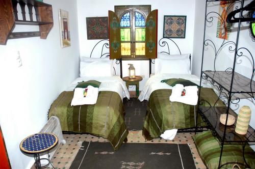 two twin beds in a room with a window at Riad Lahboul in Meknès