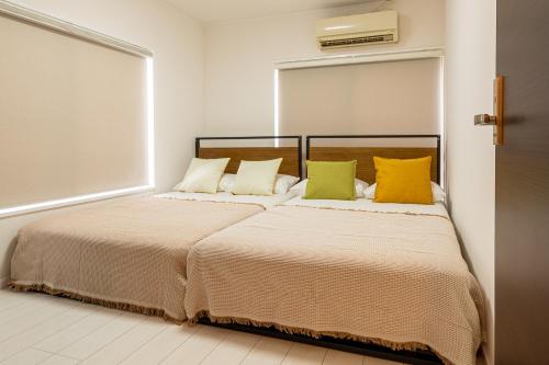 a bedroom with two beds with yellow and green pillows at 上北沢戸建て in Tokyo