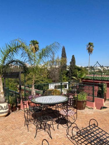 a patio with a table and chairs and palm trees at Riad Lahboul in Meknès