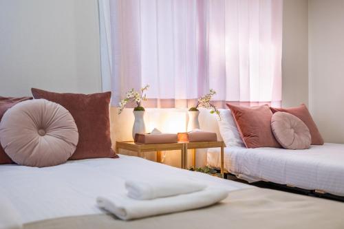 a bedroom with two beds with pillows and a window at MIYU 繁花 near USJ in Osaka