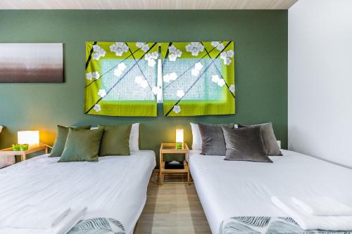 two beds in a room with green walls at MIYU 繁花 near USJ in Osaka