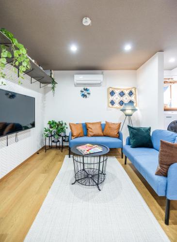 a living room with a blue couch and a tv at MIYU 繁花 near USJ in Osaka