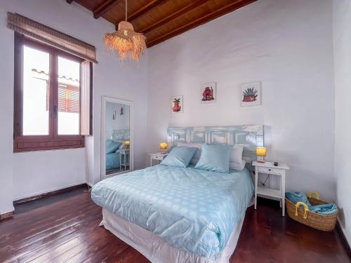 a bedroom with a bed and a window and a chandelier at Casa Libelvik en pleno centro Galdar con Terraza in Gáldar