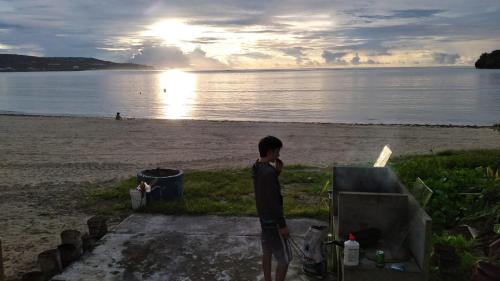 a boy standing on the beach looking at the water at Ocean Villa Guam in Tamuning