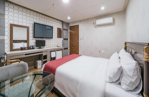 a hotel room with a bed and a tv at Seogwipo Milano in Seogwipo