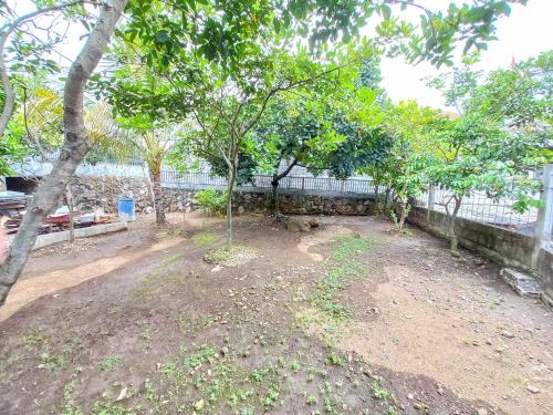 a yard with trees in front of a fence at Alif House Syariah Redpartner near Taman Dayu Pandaan in Pasuruan