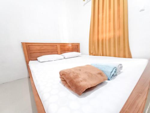a bed with white sheets and a brown blanket on it at Alif House Syariah Redpartner near Taman Dayu Pandaan in Pasuruan