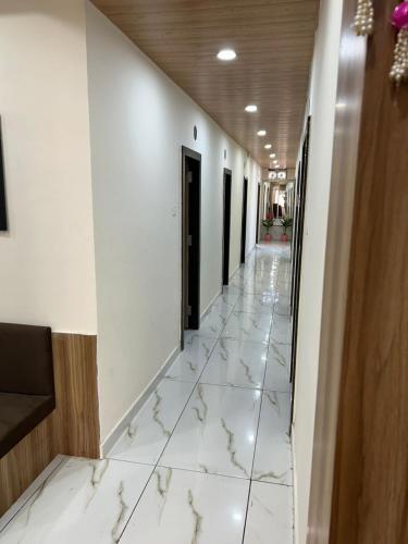 a corridor of a building with white marble floors and walls at Hotel Shivay in Indore