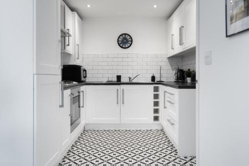 a kitchen with white cabinets and a black and white tile floor at Poets Court - Modern 2 Bedroom Apartment in West Bromwich