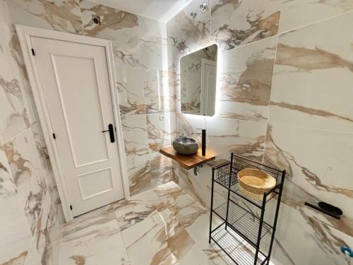 a bathroom with marble walls and a mirror at Vivienda turística Jaén Interior ÁTICO in Andújar