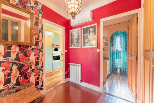 a hallway with a red wall with a painting on it at Appart face au Palais des Papes in Avignon