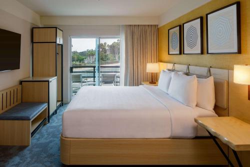 a hotel room with a large bed and a balcony at Hilton Garden Inn Dana Point Doheny Beach in Dana Point