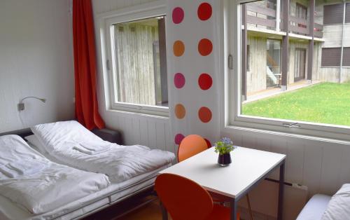 a room with two beds and a table and a window at Raulandsakademiet in Rauland