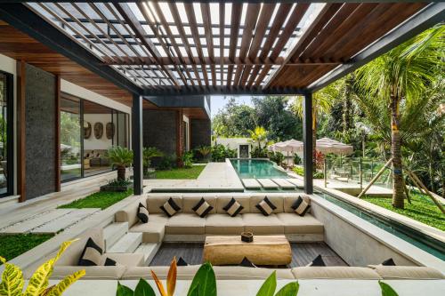 an outdoor patio with couches and a pool at Villa So Hum by BaliSuperHost in Ubud