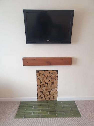 a flat screen tv on a wall with a fireplace at Modern Brixington 2 Bed, 5 minutes from the beach in Lympstone