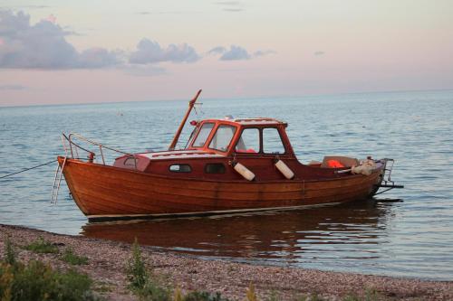 a wooden boat sitting on the shore of the water at Pruuli Holiday Farm in Sõru
