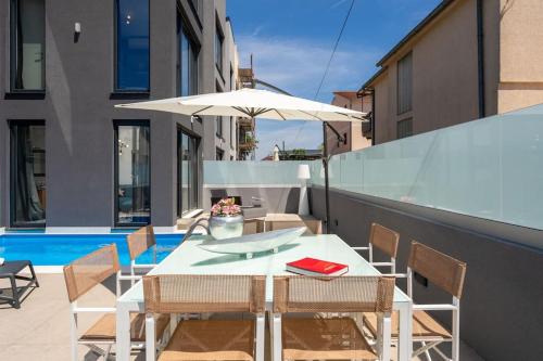 un tavolo bianco con sedie e ombrellone su un balcone di Casa Brave by Briskva a Funtana