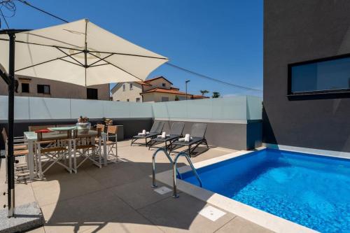 patio con piscina, tavolo e ombrellone di Casa Brave by Briskva a Funtana