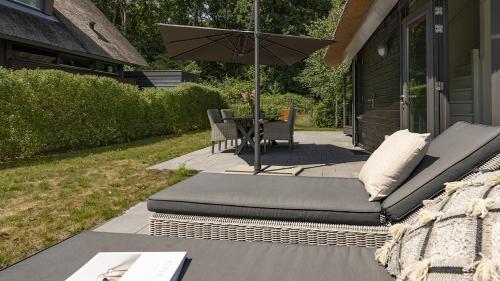 a patio with a couch and a table with an umbrella at Dutchen Villapark Mooi Schoorl in Schoorl