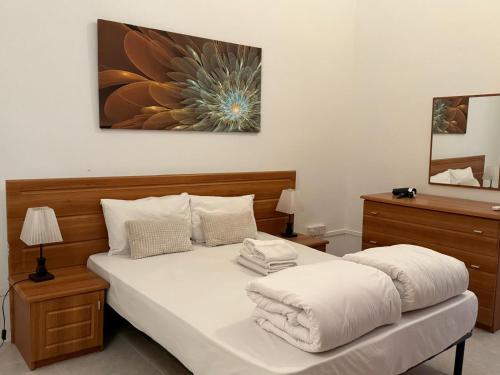 a bed with white sheets and pillows in a bedroom at Vallettastay City break apartments in Valletta
