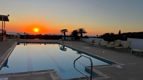 a large swimming pool with a sunset in the background at Nayia Paradise Villa! Best Villa in Cyprus in Paphos City