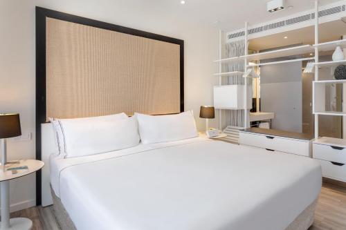 a white bedroom with a large bed and a desk at Meliá South Beach in Magaluf