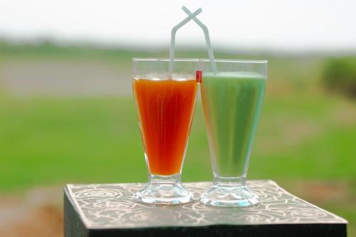 two drinks in glasses sitting on a table at Lake Side Resort in Kekirawa