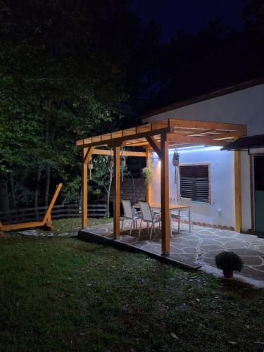 a pergola with chairs and a table in a yard at night at Vikendica WoodNook Kosmaj - Šumski kutak in Sopot