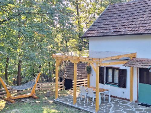 a patio with a wooden pergola next to a house at Vikendica WoodNook Kosmaj - Šumski kutak in Sopot