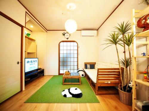 a living room with a cow laying on a green rug at 君子屋竹Hotel l 5 Min to USJ l Near Umeda&Nipponbashi l 2bedroom villa l Direct Airport Access in Osaka