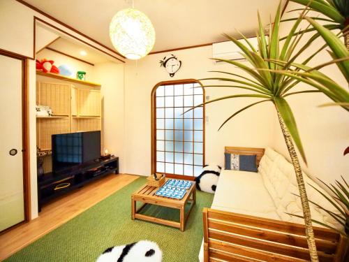 a living room with a bed and a potted plant at 君子屋竹Hotel l 5 Min to USJ l Near Umeda&Nipponbashi l 2bedroom villa l Direct Airport Access in Osaka