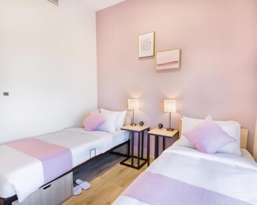 two beds in a small room with two lamps at The Myriad Muscat - Female Only ذا ميرياد مسقط - للنساء فقط in Seeb