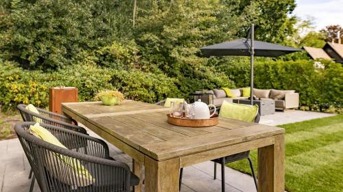 a wooden table with chairs and an umbrella at Dutchen Villapark Mooi Schoorl in Schoorl