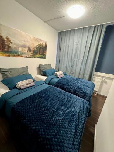 una camera con due letti con coperte blu e una finestra di Candy Vibe Inn a Norimberga